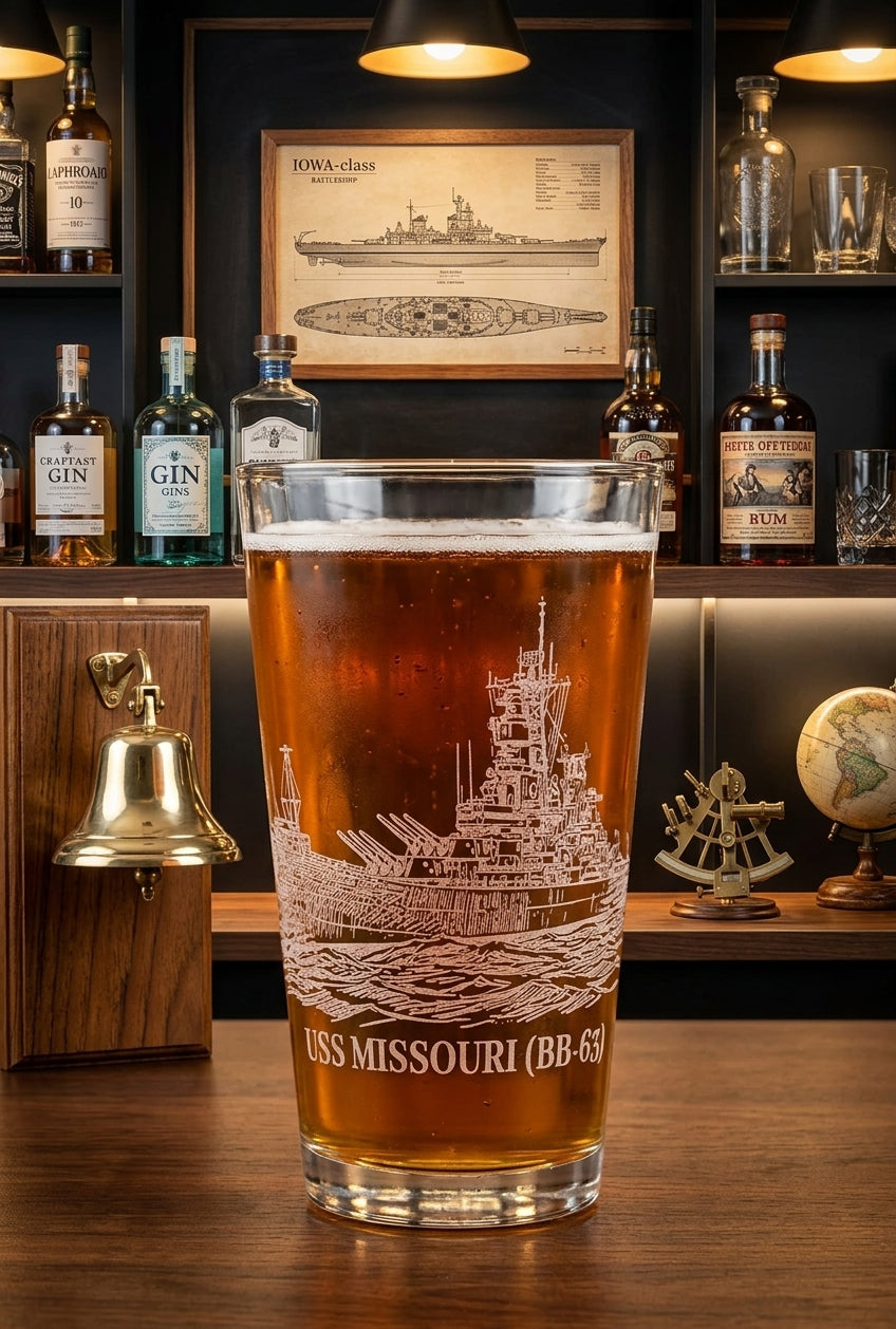 16 oz pint glass laser engraved with the USS MISSOURI (BB-63) battleship, displayed on a wooden bar with a home bar background.