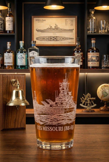 16 oz pint glass laser engraved with the USS MISSOURI (BB-63) battleship, displayed on a wooden bar with a home bar background.